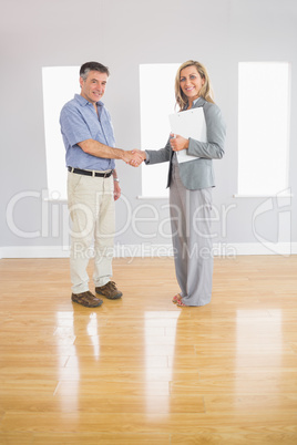 Pleased realtor and buyer shaking hands
