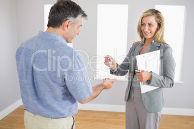 Pleased realtor holding a briefcase and giving a key to a buyer