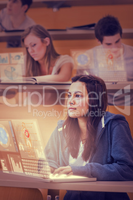 Concentrated pretty student working on her futuristic laptop