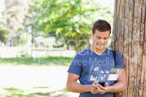 Smiling handsome student using his digital smartphone