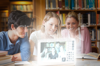 Cheerful college friends watching photos on digital interface