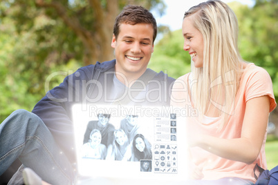 Smiling young couple watching photos together on digital interfa