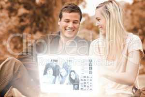 Happy young couple watching photos together on digital interface