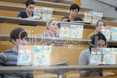 Focused students in lecture hall working on their futuristic tab