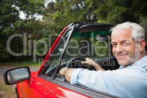 Smiling handsome man driving red cabriolet
