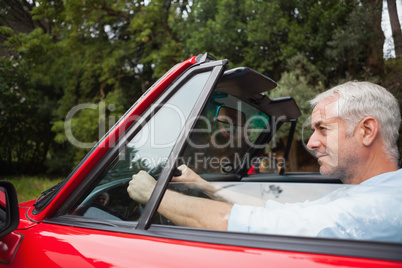 Content handsome man driving red cabriolet