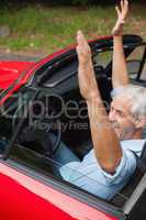 Cheerful handsome man enjoying his red cabriolet