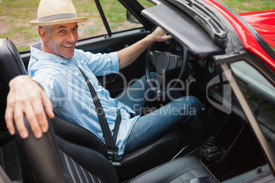 Cheerful handsome man posing in red convertible