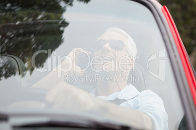 Smiling handsome man in red convertible having phone call