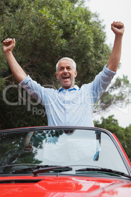 Smiling mature man enjoying his red convertible