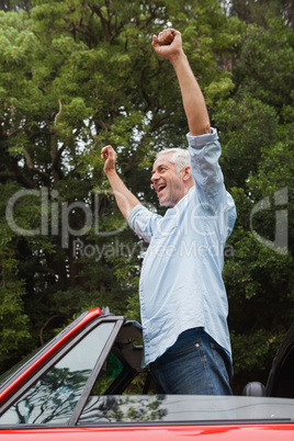 Happy mature man enjoying his red convertible