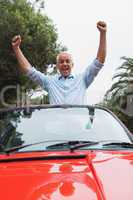 Cheerful mature man enjoying his red convertible