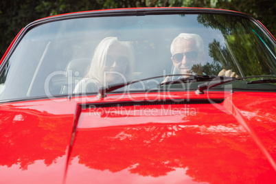 Smiling mature couple in red cabriolet