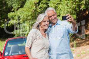 Cheerful mature couple taking pictures of themselves