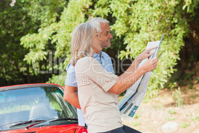 Smiling mature couple reading map together