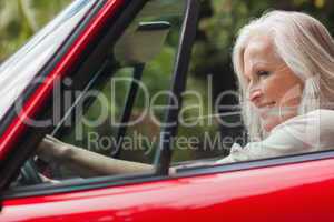 Cheerful mature woman driving red convertible