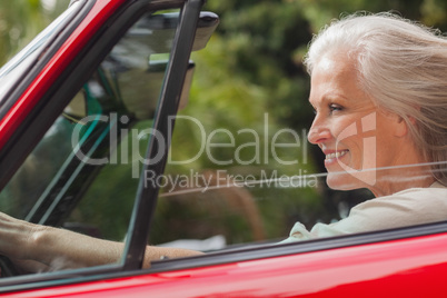 Smiling mature woman driving red convertible