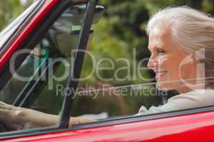 Smiling mature woman driving red convertible