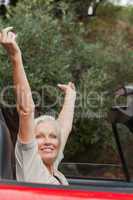 Happy mature woman enjoying her red convertible
