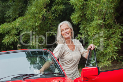 Cheerful mature woman getting off her convertible