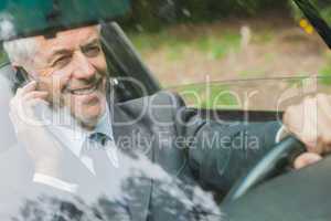 Smiling businessman on the phone driving