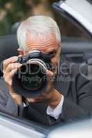Mature paparazzi taking picture with professional camera