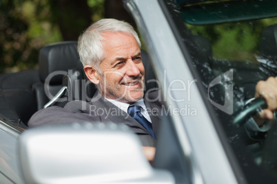 Smiling businessman driving expensive cabriolet