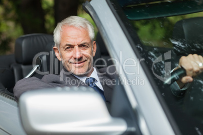 Content businessman driving expensive cabriolet