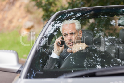 Content businessman on the phone driving expensive cabriolet
