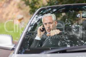 Content businessman on the phone driving expensive cabriolet