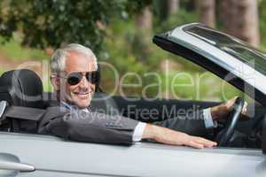 Smiling mature businessman driving classy cabriolet