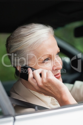 Peaceful businesswoman on the phone driving classy car