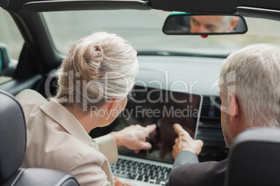 Business people working together on laptop in classy cabriolet
