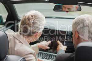 Business people working together on laptop in classy cabriolet