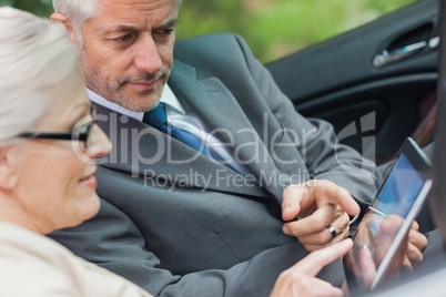Partners working together on tablet in classy convertible