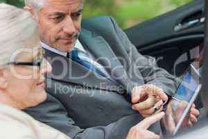 Partners working together on tablet in classy convertible