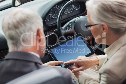 Mature partners working together on tablet in classy convertible