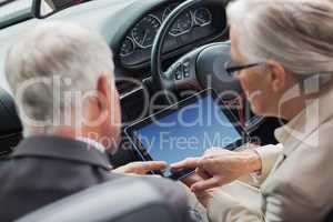 Mature partners working together on tablet in classy convertible