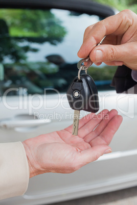 Close up on business man giving his keys to his female partner