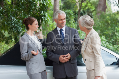 Smiling business people talking together by classy cabriolet