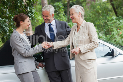 Cheerful business people talking together by classy cabriolet