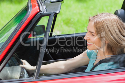 Smiling woman driving red cabriolet