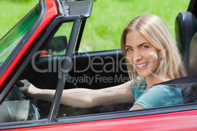Cheerful woman driving red cabriolet