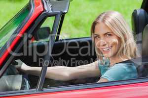 Cheerful woman driving red cabriolet