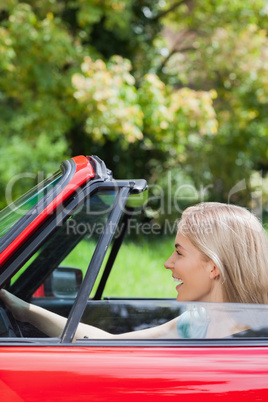 Happy woman driving red cabriolet