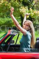 Smiling blonde enjoying her red cabriolet