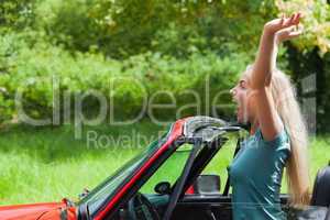 Cheerful blonde enjoying her red cabriolet