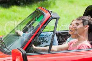 Smiling young couple having a ride in red cabriolet