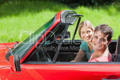 Cheerful young couple having a ride in red cabriolet