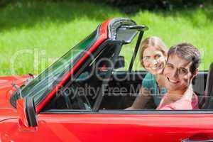 Cheerful young couple having a ride in red cabriolet